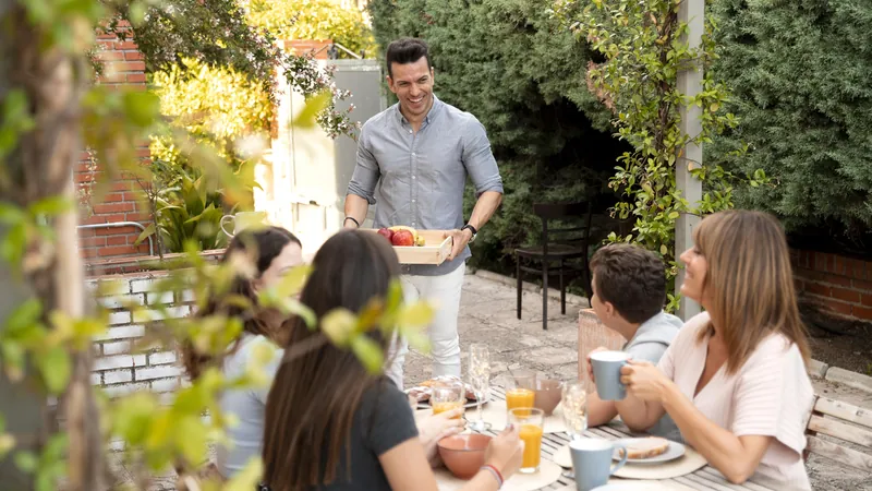 Familie beim Mittagessen an einem langen Tisch im Garten